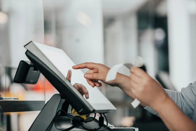 Hands working a point-of-sale screen