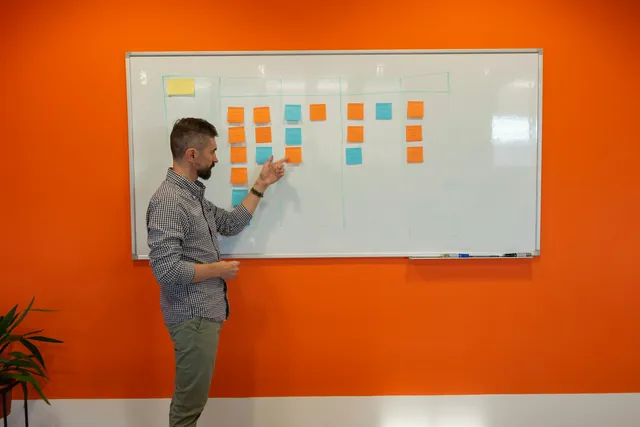 A man arranging sticky notes on a whiteboard