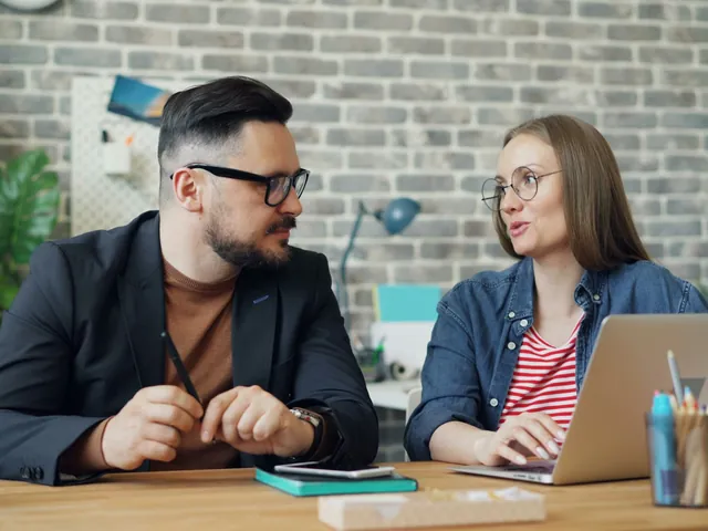 Two people talking through a plan at a desk